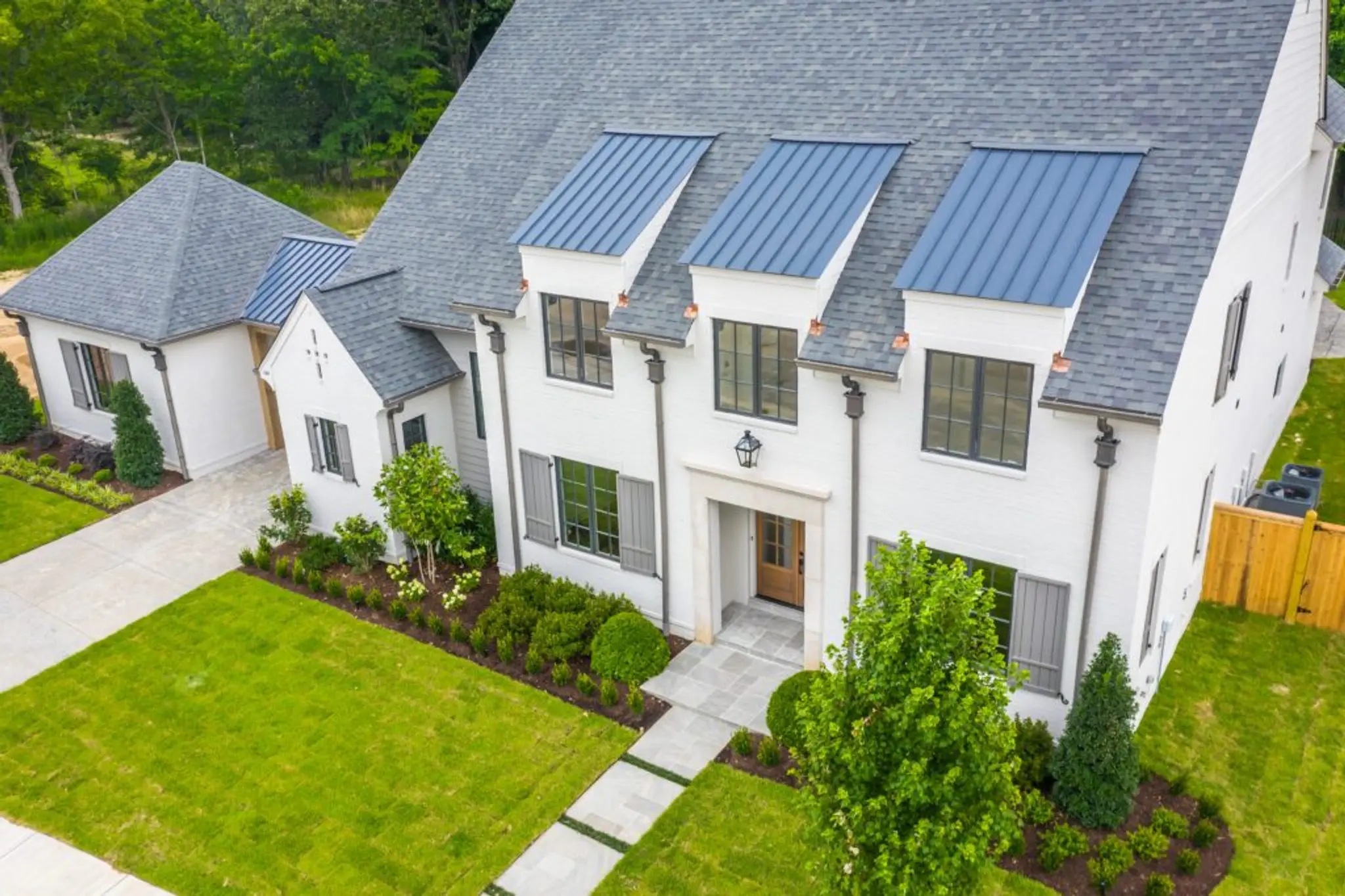 Exterior white brick home with exquisite details including a porte-cochere, metal roofs, and limestone