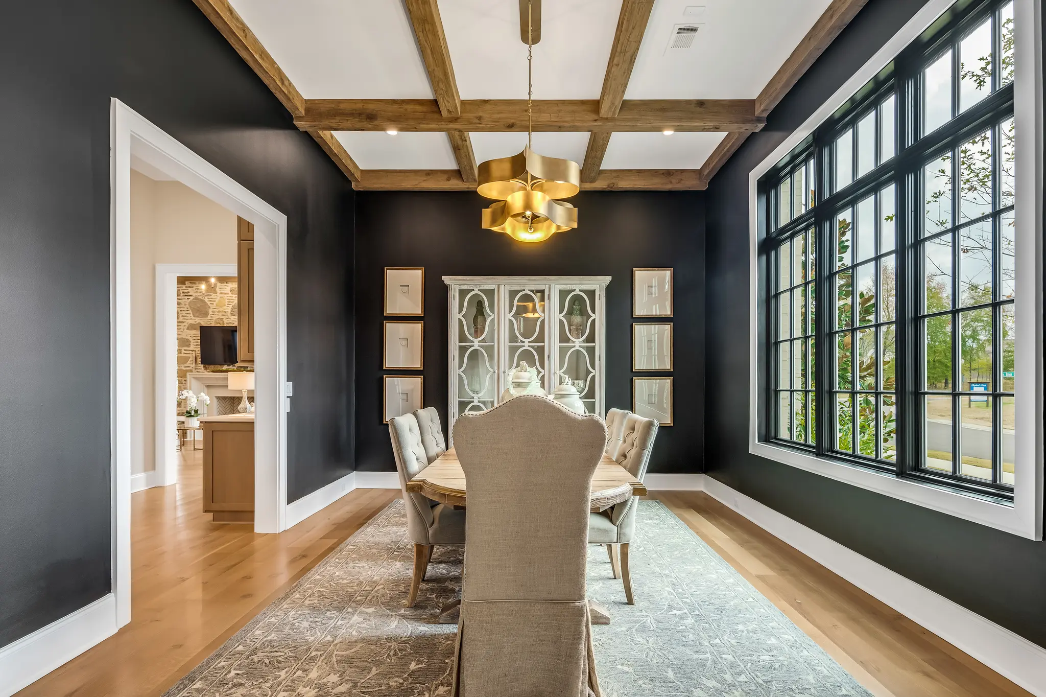 Dramatic dining room painted black with bright windows, cedar beams, and a stunning center light