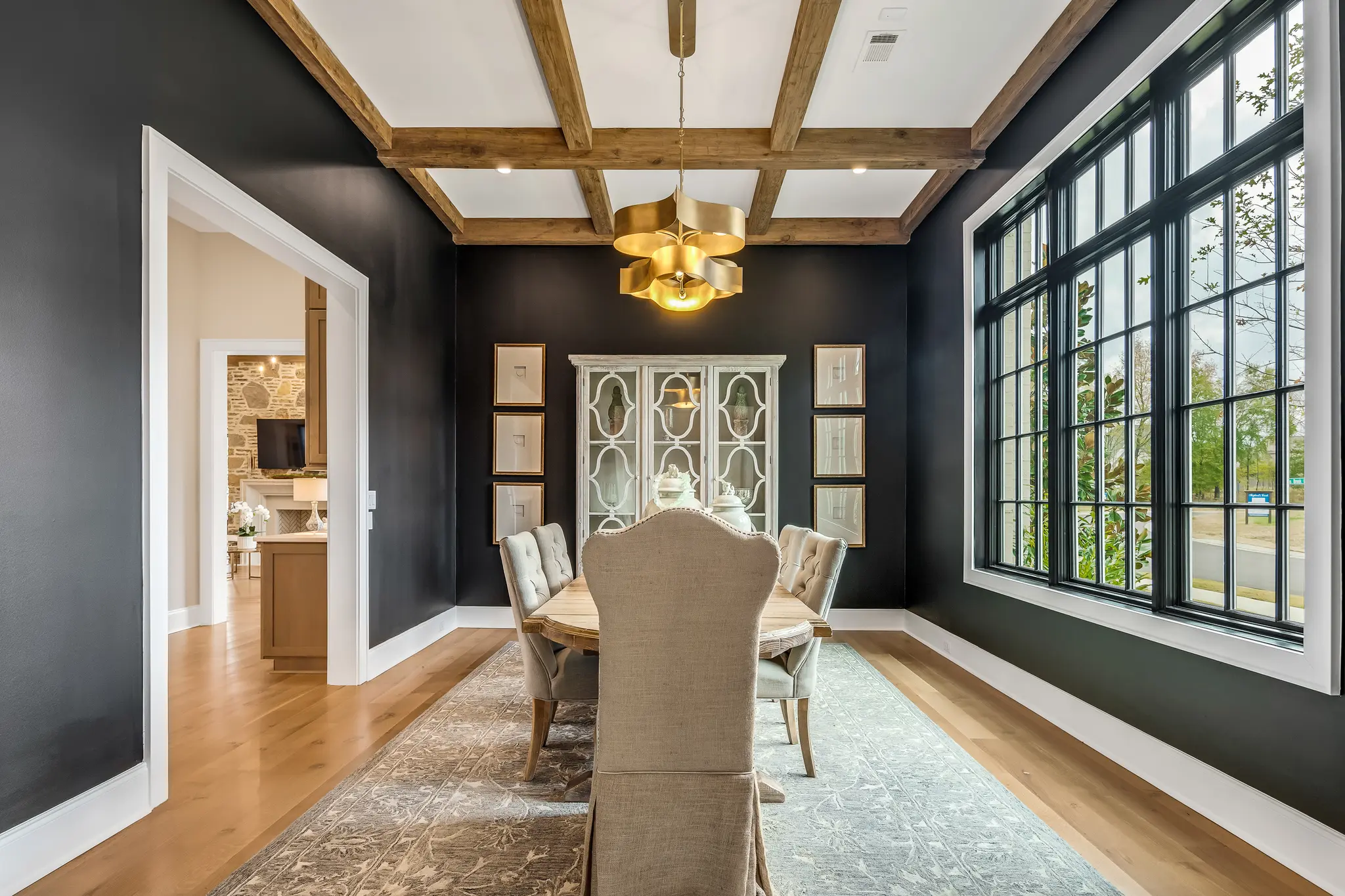 Dramatic dining room painted black with bright windows, cedar beams, and a stunning center light