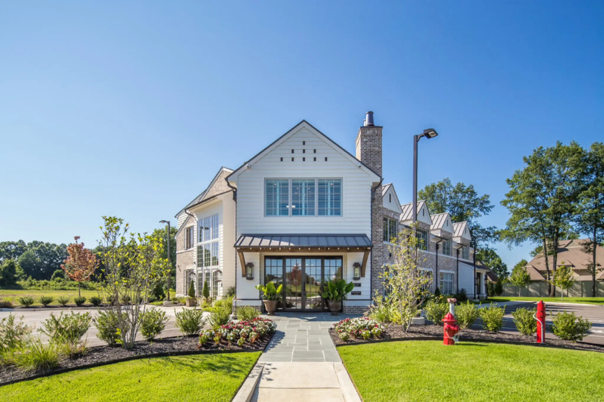 Exterior of Magnolia Homes Design Center with green grass, metal roof, stately brick, and gorgeous siding