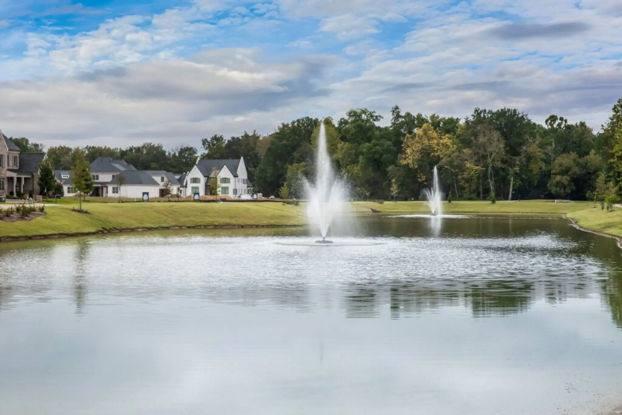 Luxury Community amenities, including a glimmering pond with two fountains and a walking trail