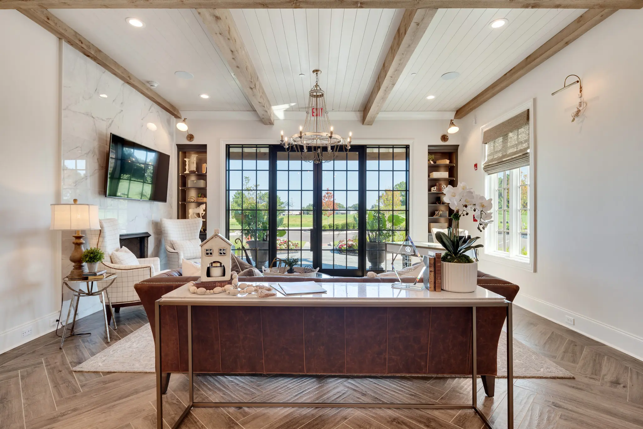 Front entry foyer of Magnolia Homes Design Center with glass iron doors, cedar beams, and tile with a herringbone design.