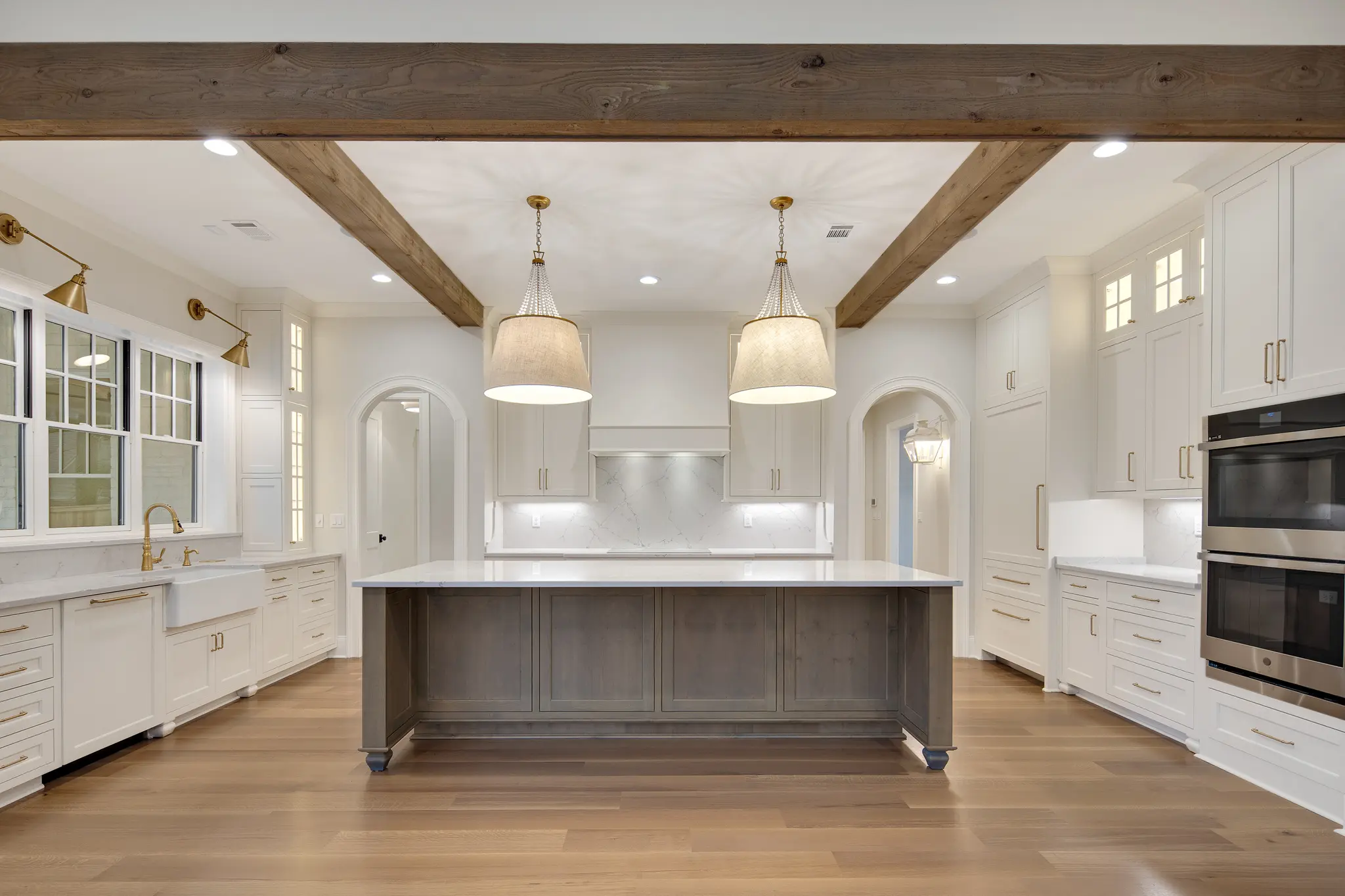 Award-winning kitchen with dark wood island, creamy white cabinetry, beautiful pendant lights, and shining countertops