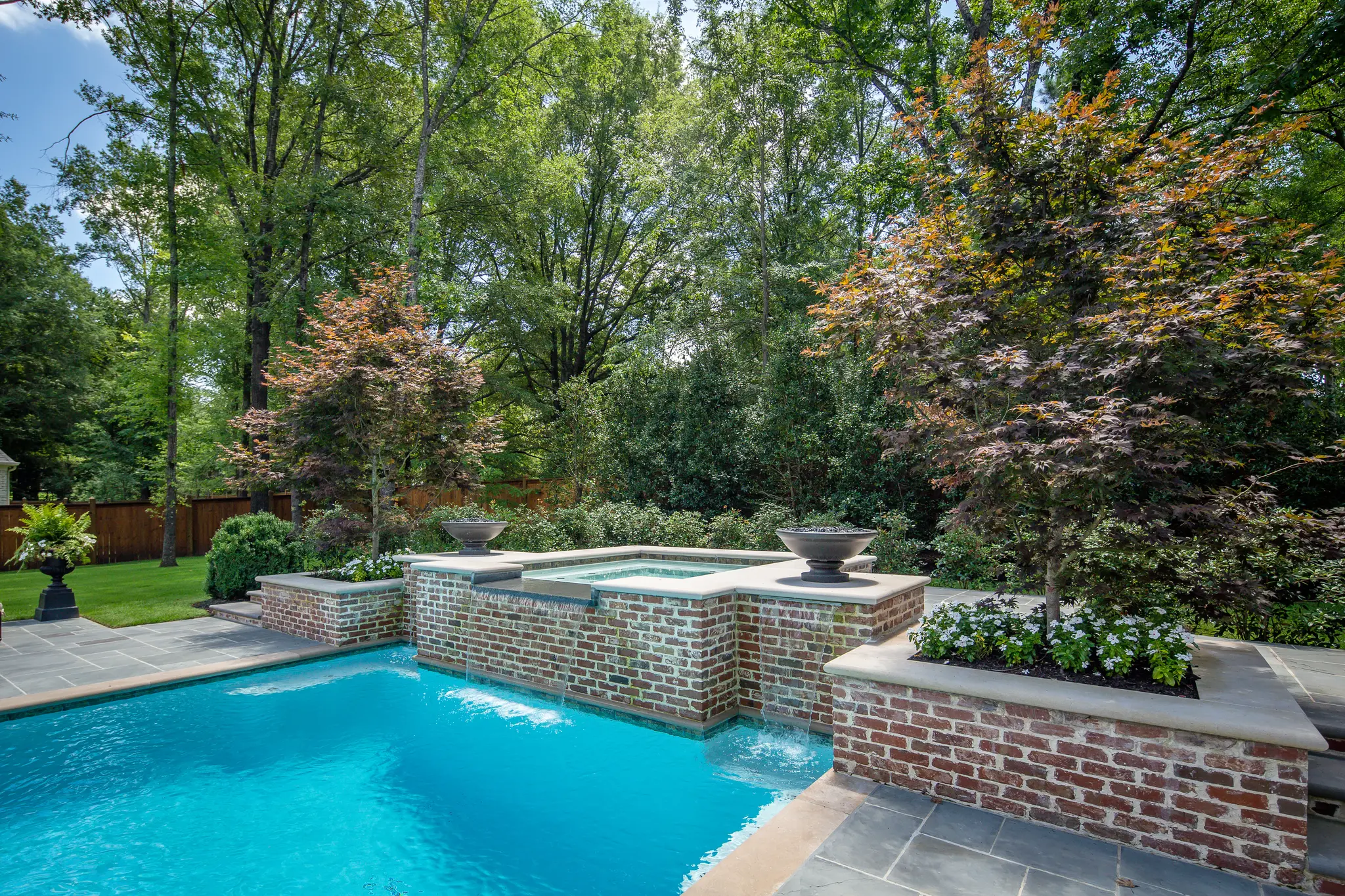 Babbling hot tub overflowing into a blue pool in a vibrant backyard