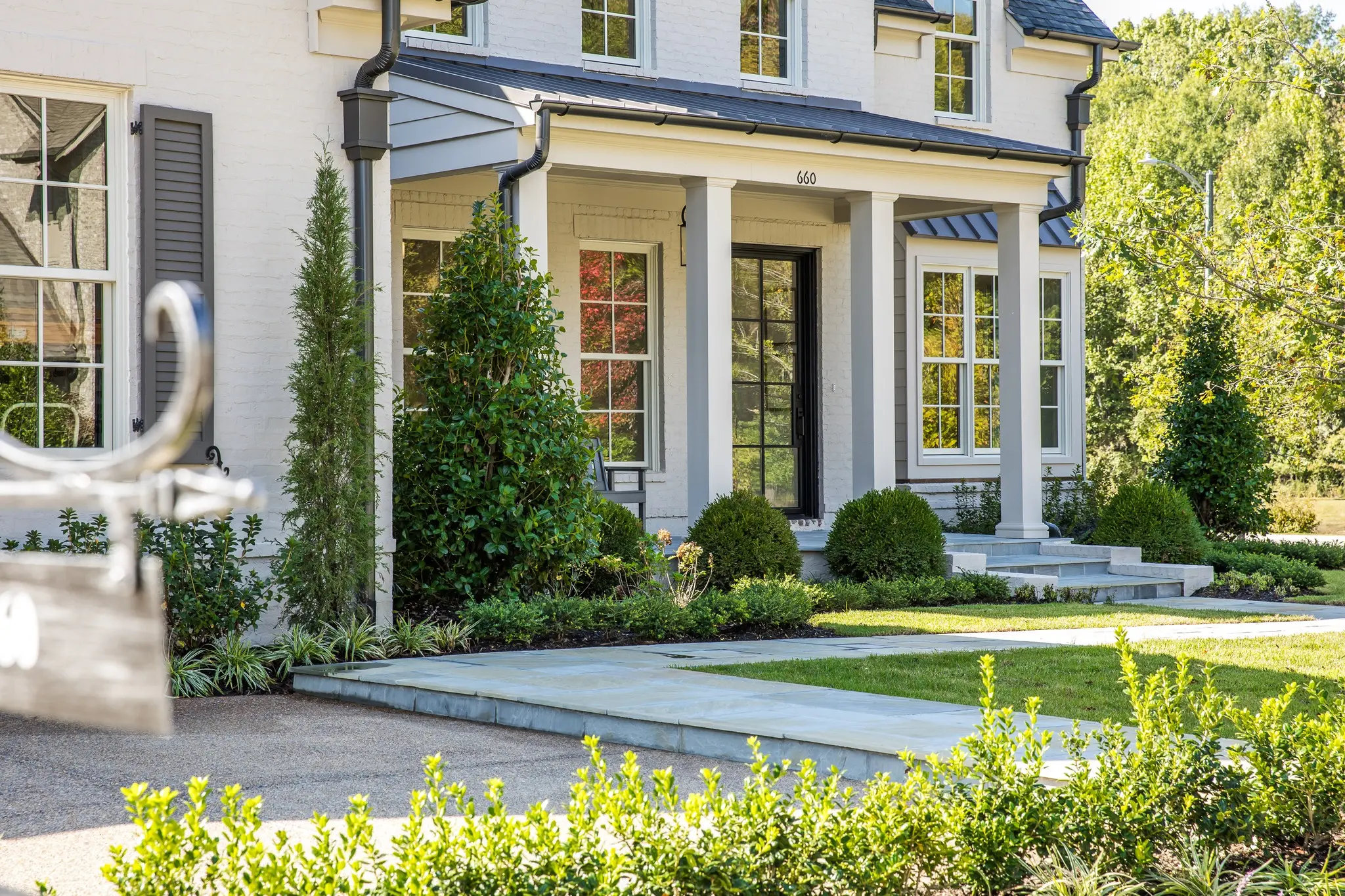 Stunning view of exterior of a home with front porch, columns, blue stone, and metal roof