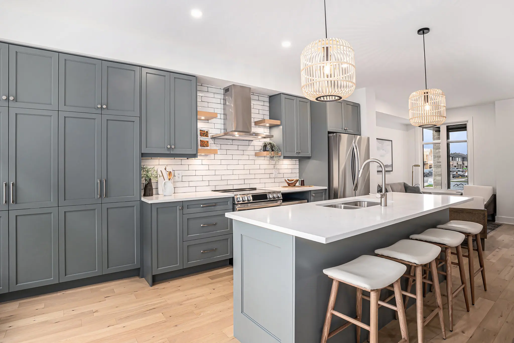 Modern kitchen with gray cabinets, white island, pendant lights, and wood bar stools