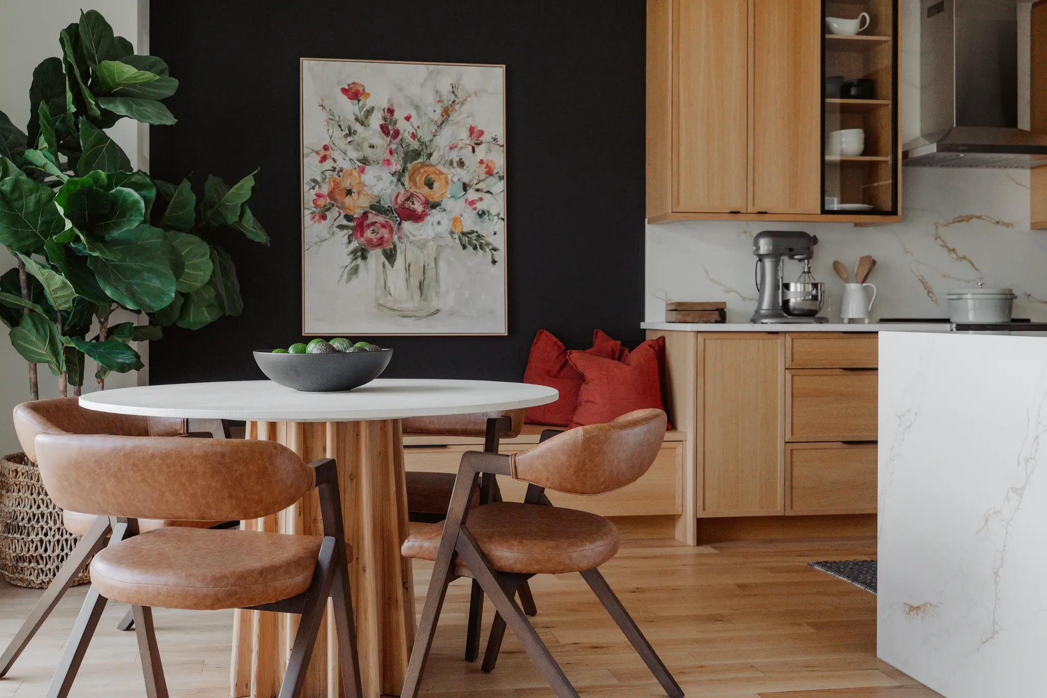 Modern dining area with round table, leather chairs, wood cabinets, and black accent wall