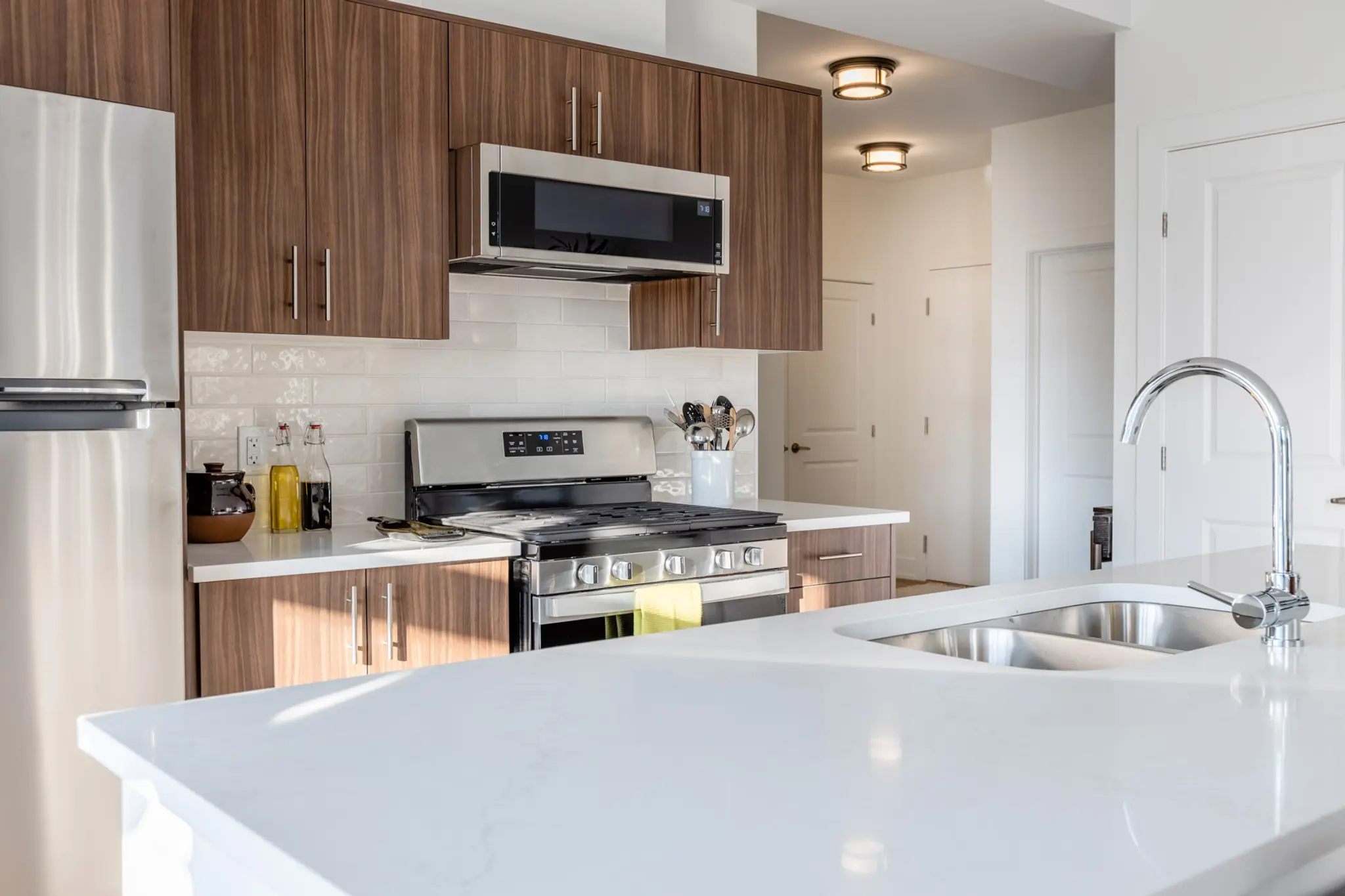 Modern kitchen with wood cabinets, white island countertop, and stainless steel appliances