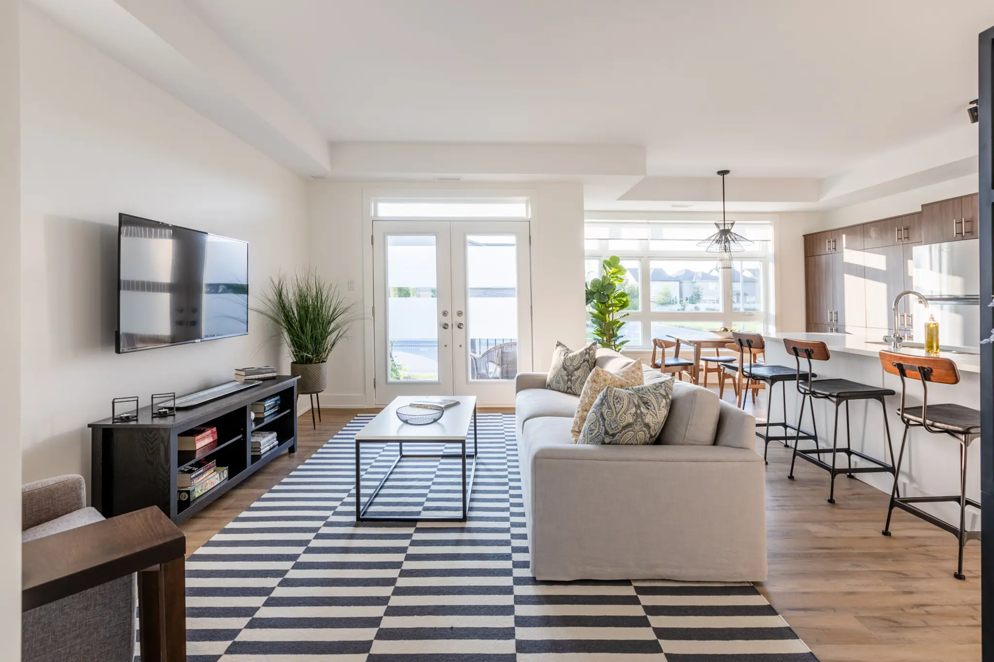 Open-concept living room and kitchen with striped rug, breakfast bar, and natural light