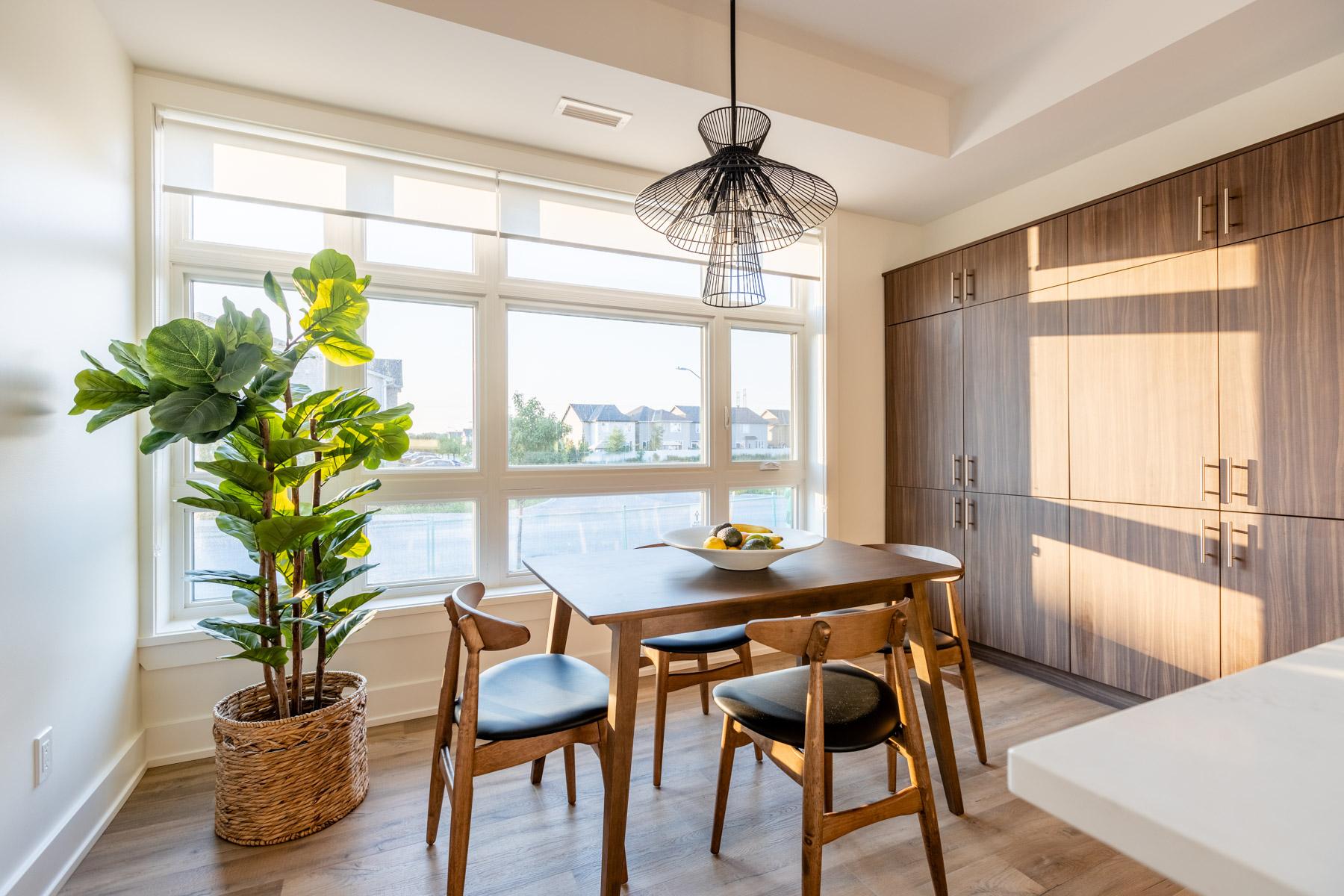 Sunlit breakfast nook with wood dining table, large windows, and floor-to-ceiling cabinetry