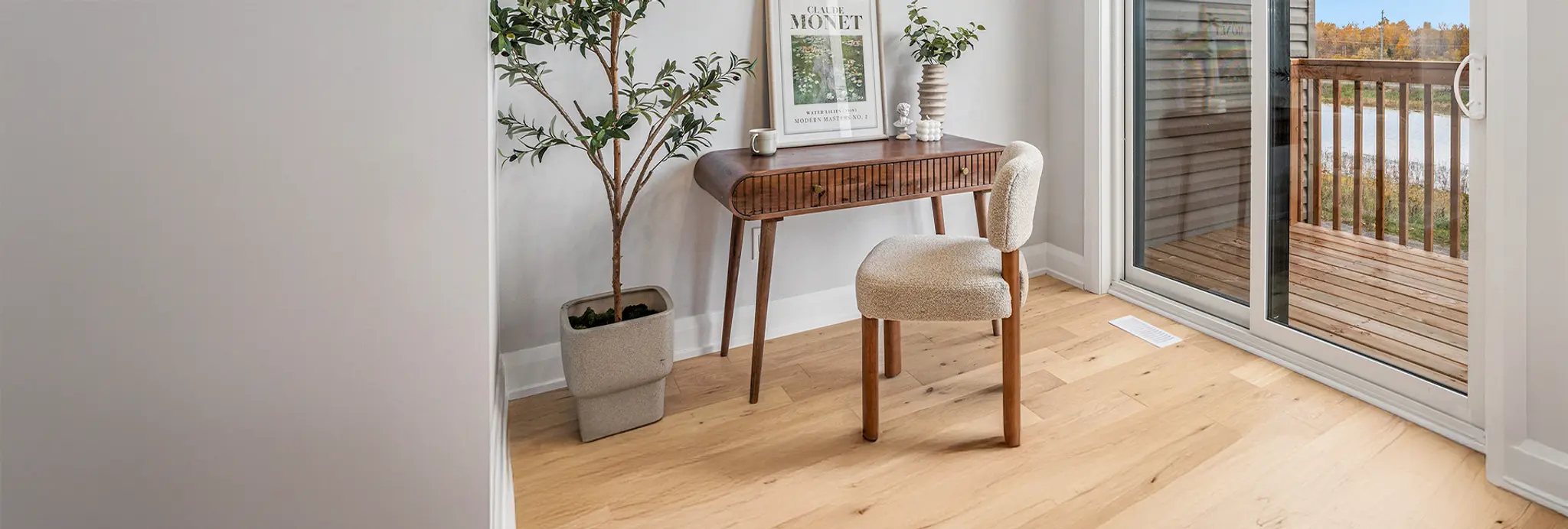Compact home office nook with wood desk, upholstered chair, and balcony access through sliding doors