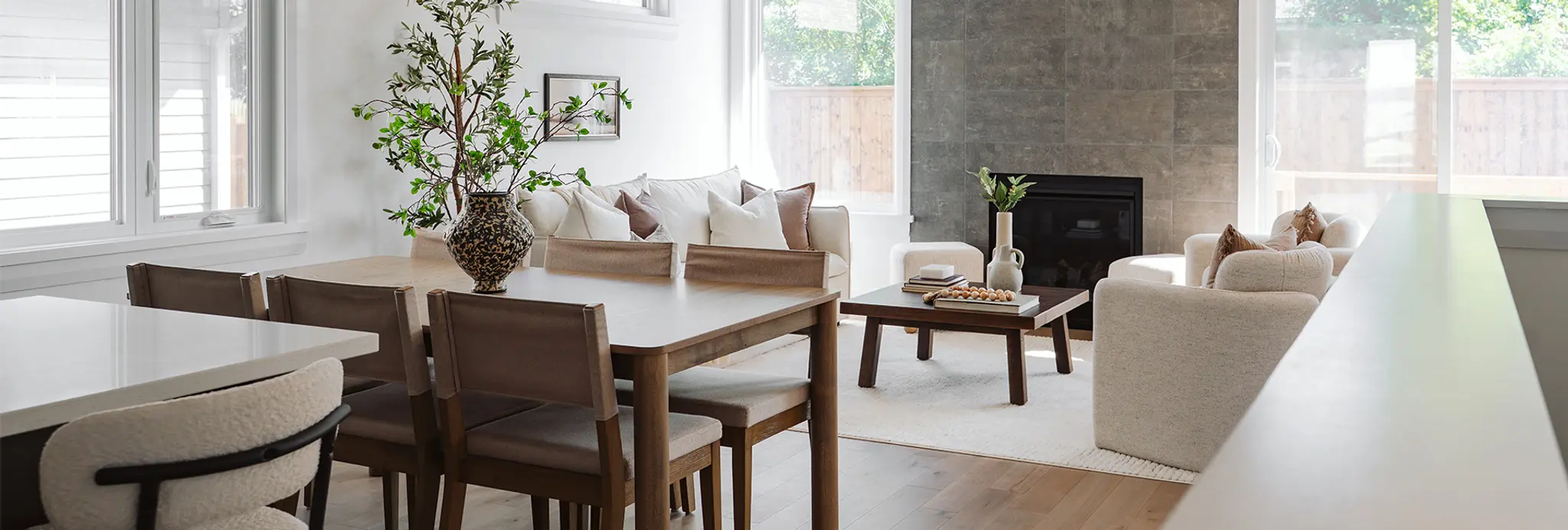 Open-concept dining and living area with wood table, fireplace, and neutral seating